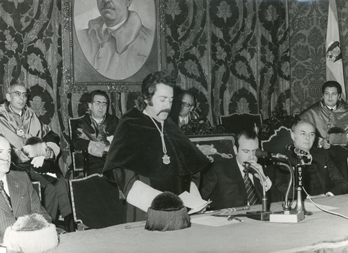 El   Rector Juan Díez Nicolás en pie y con traje académico, dirigiendo unas   palabras durante la celebración de un acto académico (1976)