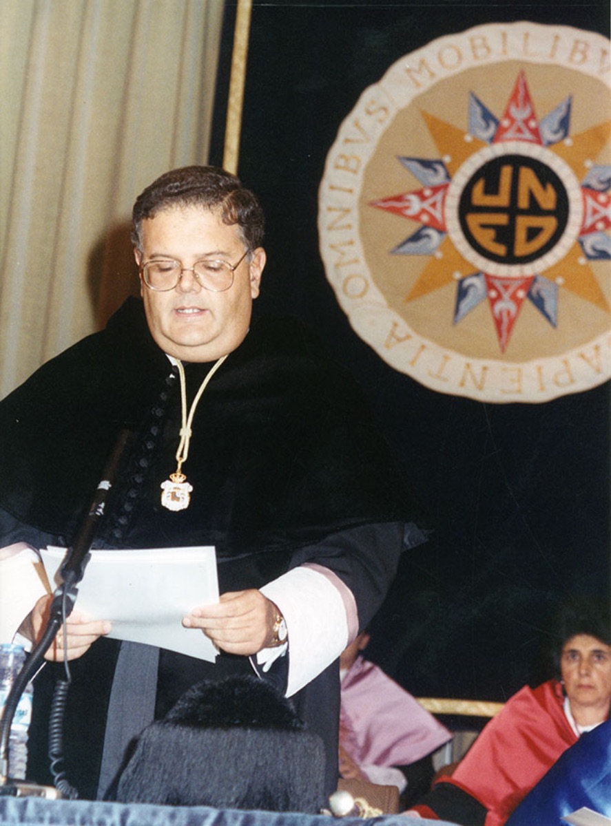 Mariano   Artés, Rector de la UNED, en pie pronunciando unas palabras durante el acto   de apertura del curso académico 1991/1992 (Imagen de Estudio Fotográfico   Portillo, 1991)