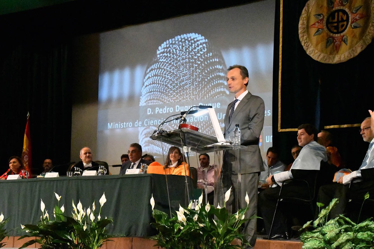 Pedro   Duque, Ministro de Ciencia, Innovación y Universidades, realiza su discurso   en el acto de apertura del curso académico 2019-2020, con Ricardo Mairal   presidiendo la mesa (Imagen de José Rodríguez, 2018)
